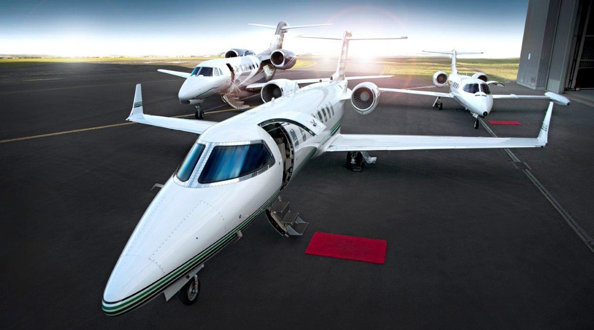 Three private jets are parked on a runway.