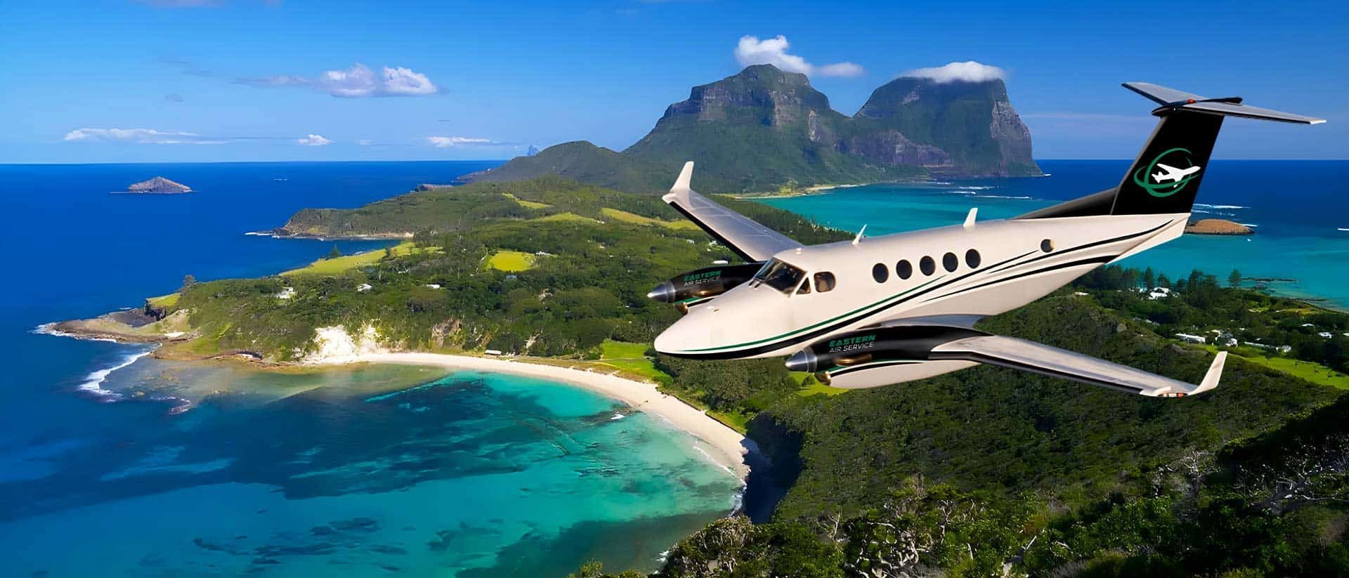 A small plane is flying over a tropical island.