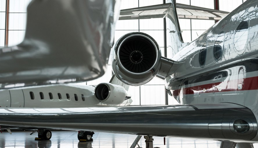 Two private jets are parked in a hangar.