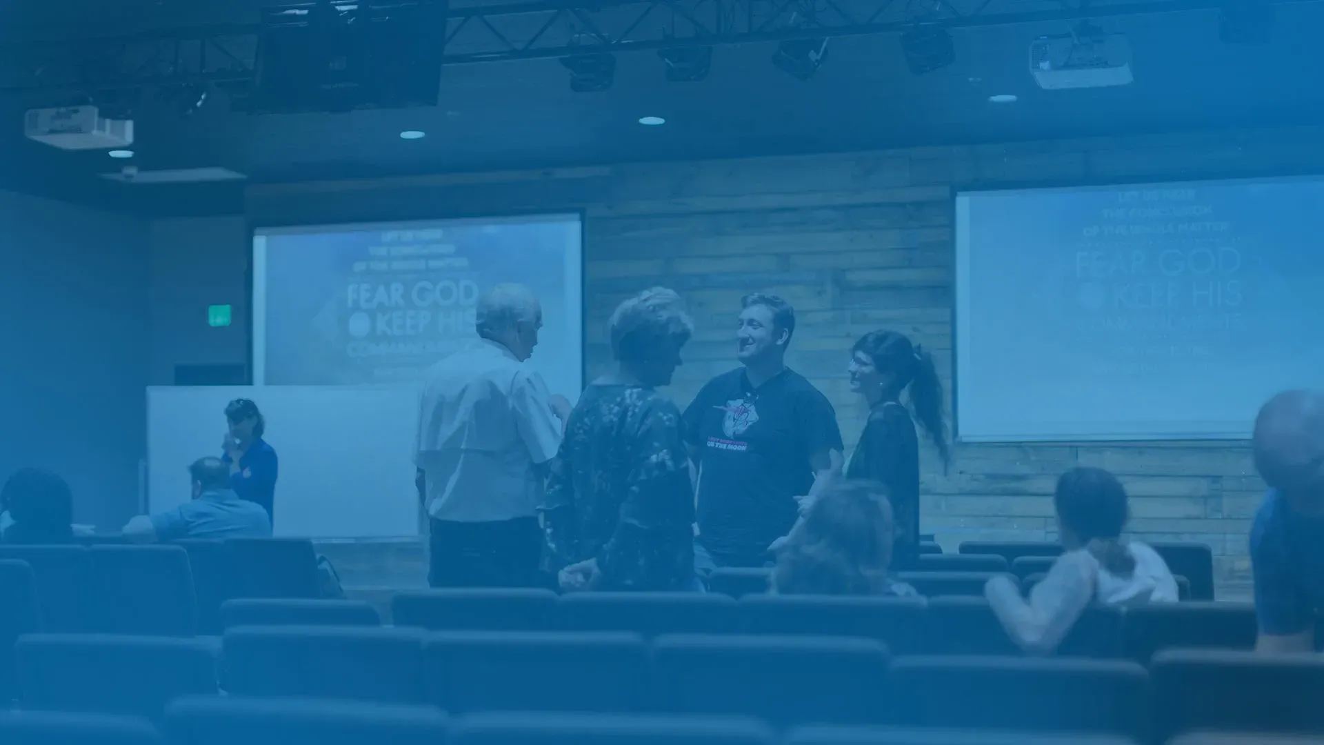 A group of people are standing in front of a large screen in an auditorium.