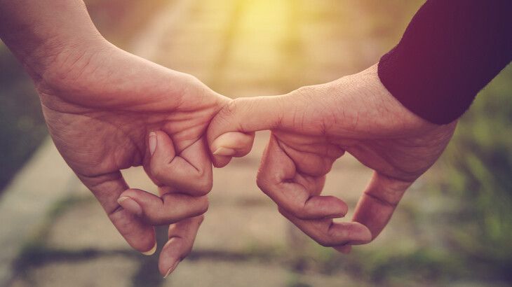 A man and a woman are holding hands with their fingers.
