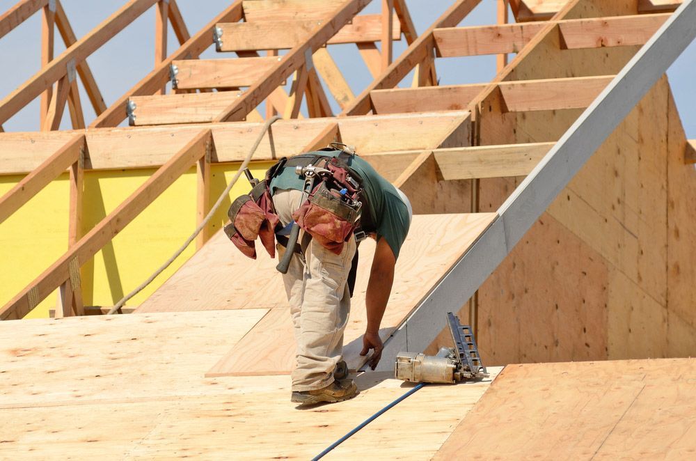 Construction Crew Working On The Roof Sheeting Of A New Two Story Home — Trussted Frames & Trusses in Port Macquarie, NSW
