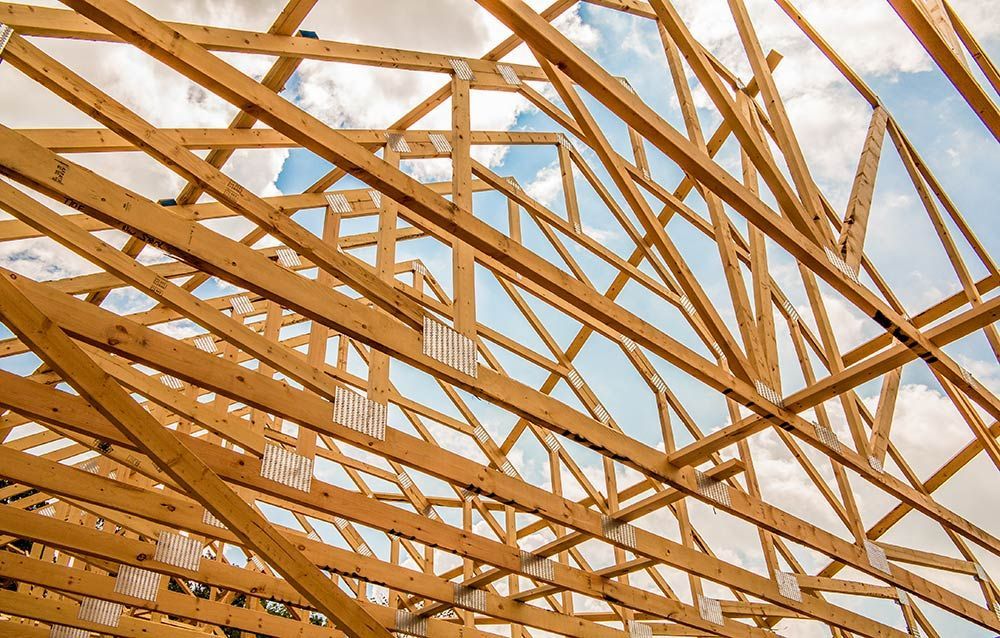 Wood House Truss Against Blue Sky With Puffy Clouds — Trussted Frames & Trusses in Port Stephens, NSW