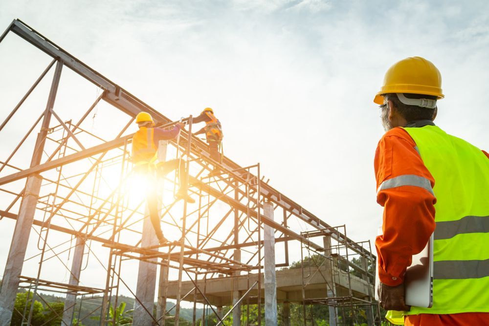 A Construction Worker Is Standing in Front of A Building Under Construction — Trussted Frames & Trusses in Bennetts Green, NSW
