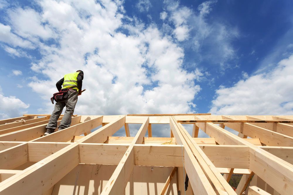 Construction Crew Working On The Roof Against Blue Sky — Trussted Frames & Trusses in Taree, NSW