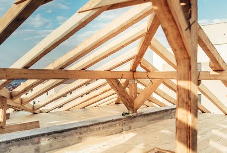 A Wooden Roof Is Being Built on Top of A Building — Trussted Frames & Trusses in Bennetts Green, NSW