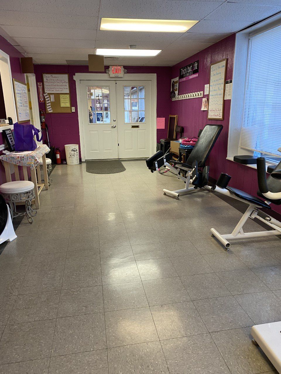Purple-walled waiting room with chairs, a window, double doors, and ceiling lights