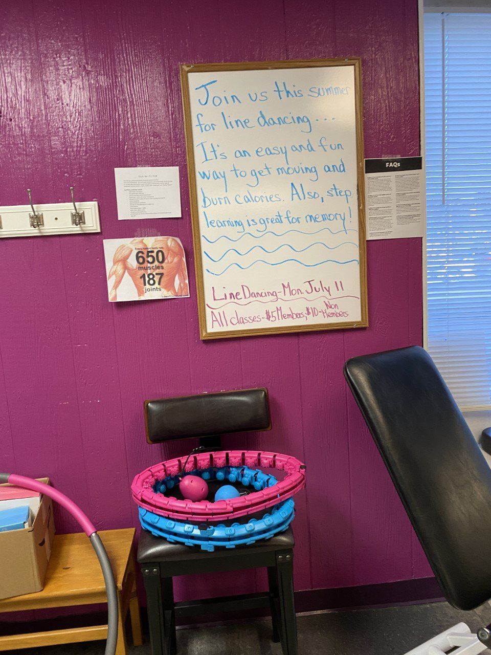 Purple wall with a whiteboard, small chair, and colorful toy rings in a playroom.