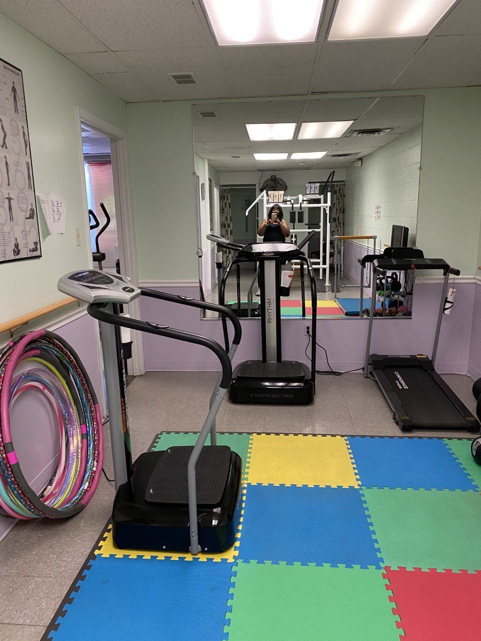 Gym room with colorful foam floor tiles, treadmills, and stacked hula hoops against the wall