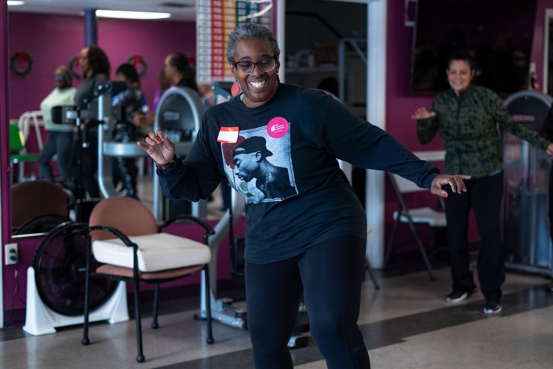 People dancing in a gym studio, with one smiling woman in the foreground holding a jump rope.