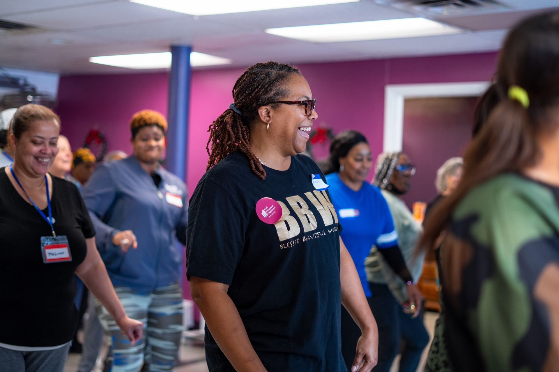 People exercising in a colorful studio, smiling and moving in a group class