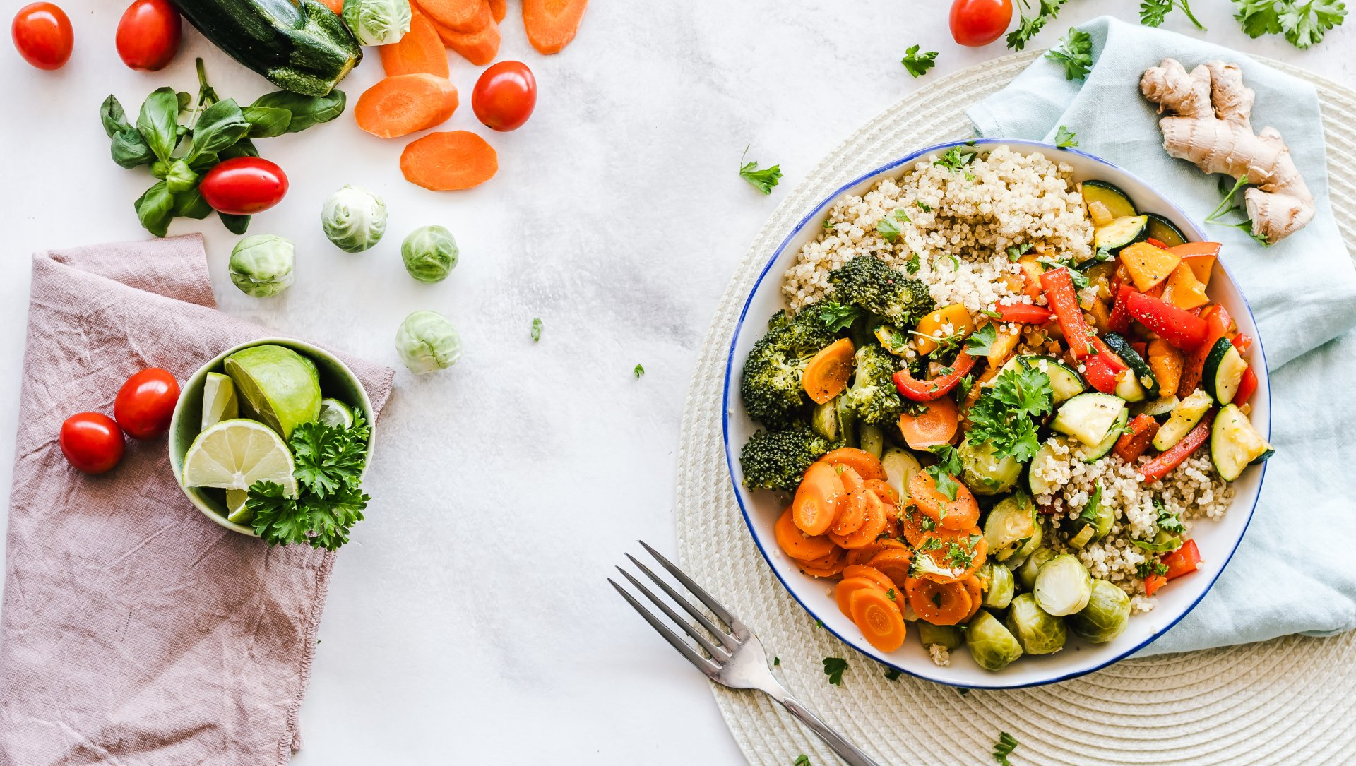Colorful salad bowl with vegetables, lime wedges, and tomatoes on a light table setting