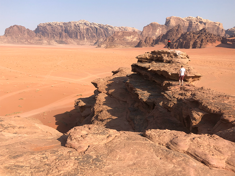 Looking out at a man standing on top of a rock in the desert