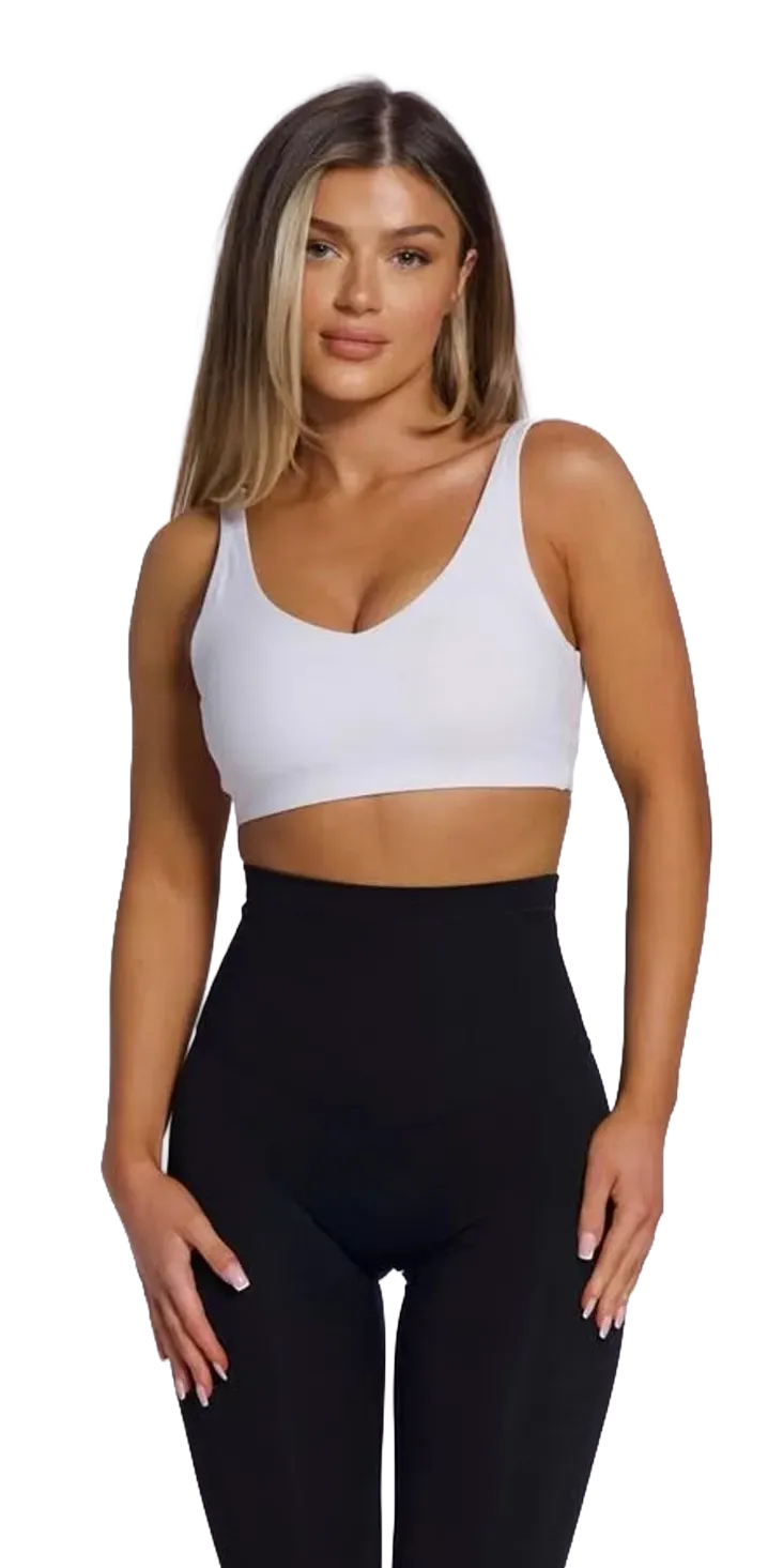 Person in white sports bra and black leggings posing against a white background
