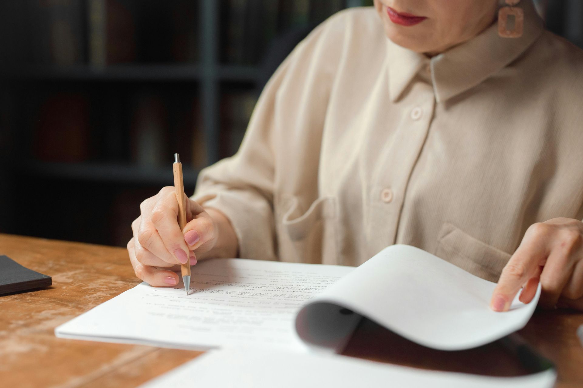 a woman is writing on a piece of paper with a pencil .