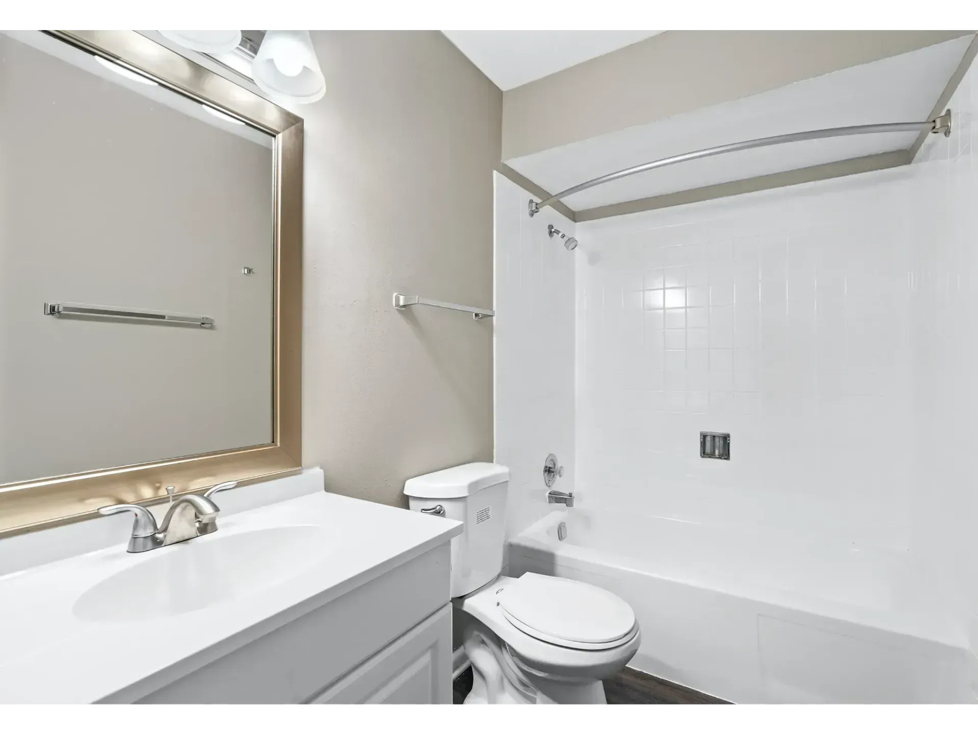 Bright bathroom with white tub, toilet, vanity sink, and large mirror, viewed from the doorway