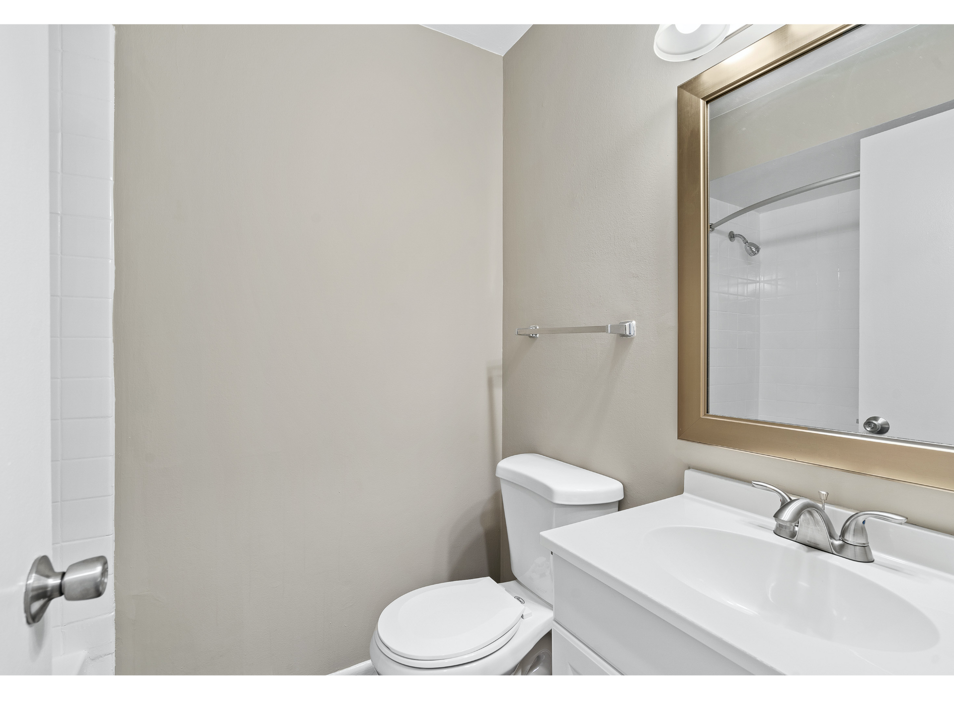 Small bathroom with toilet, sink, mirror, and beige walls