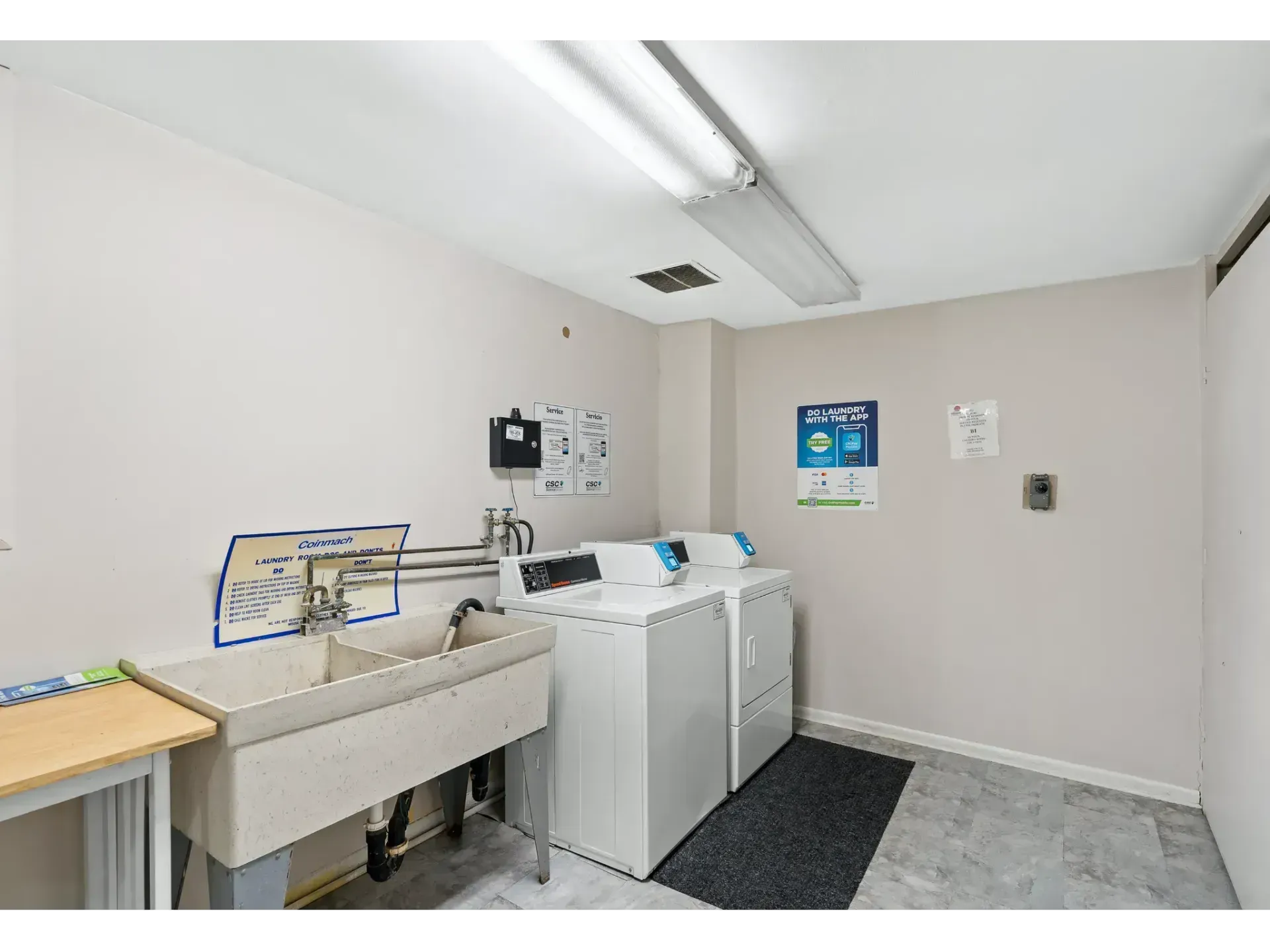 Laundry room with washer, sink, folding table, and wall-mounted equipment in a bright utility space