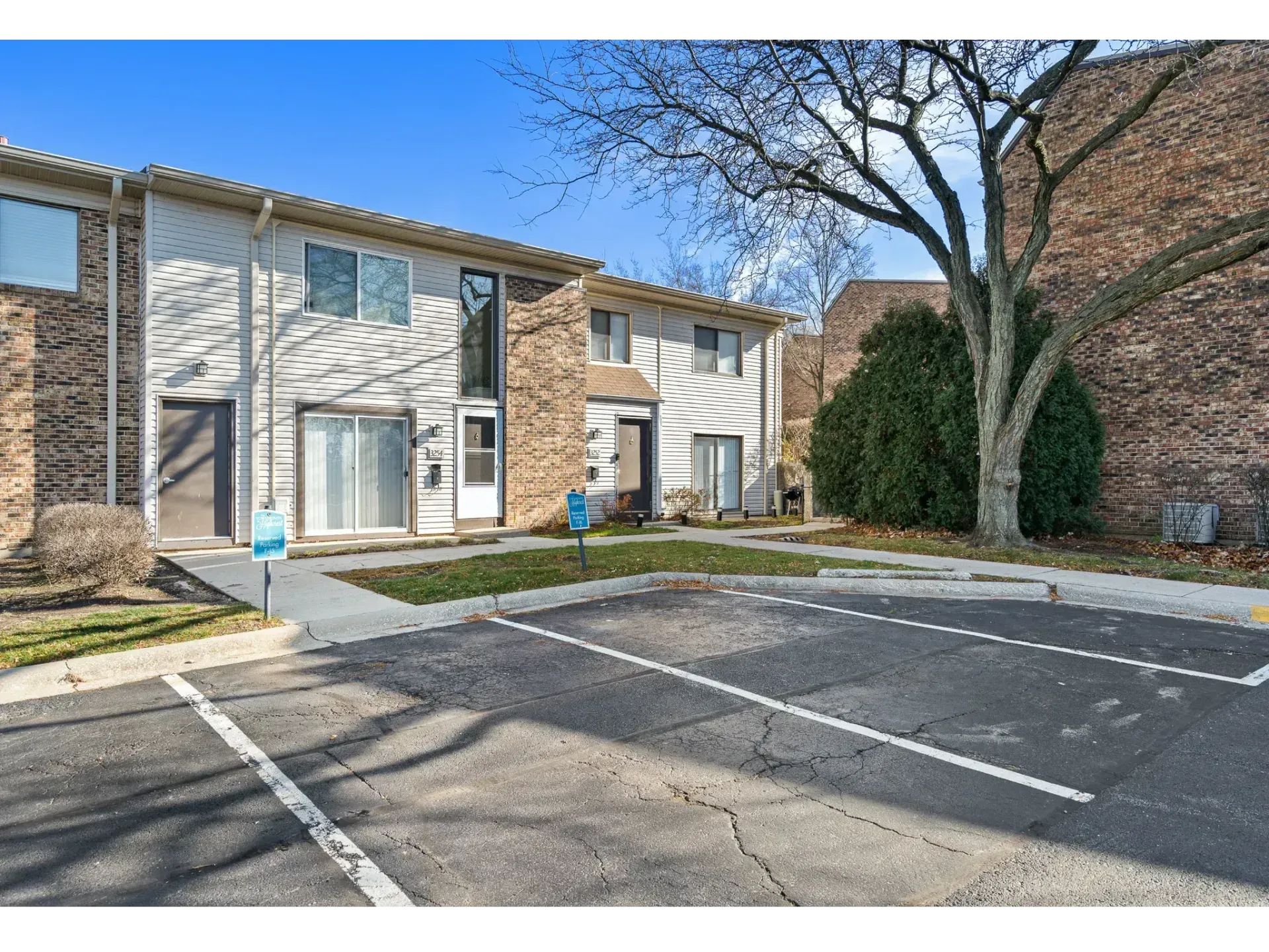 Apartment building parking lot with two-story tan townhomes and leafless trees