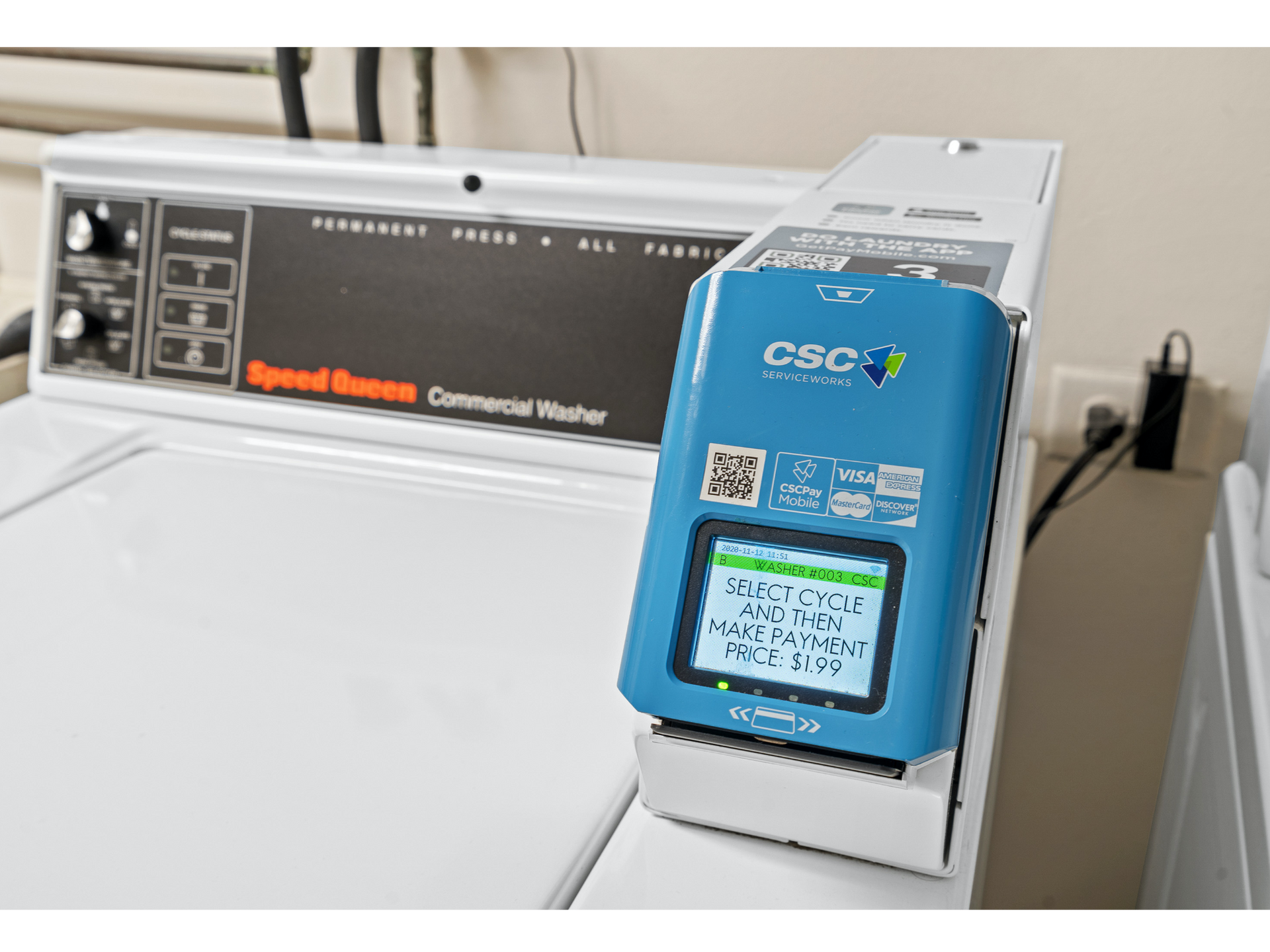 Blue CSC donation/payment kiosk mounted on a white laundromat washing machine