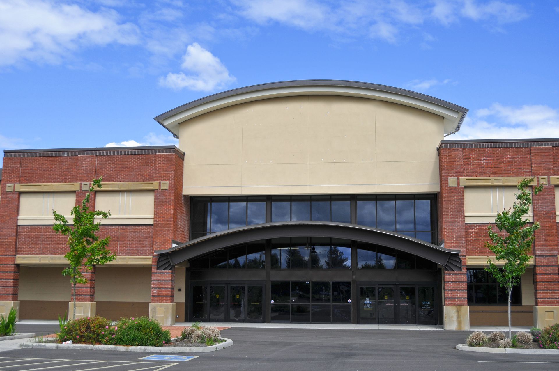 Front entrance of a modern brick building with arched tinted glass canopy and blue sky overhead in Yucaipa.