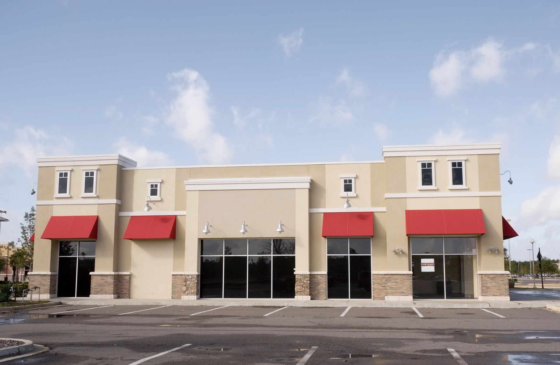 Beige commercial Yucaipa,CA storefront with red awnings and glass entrance in a parking lot