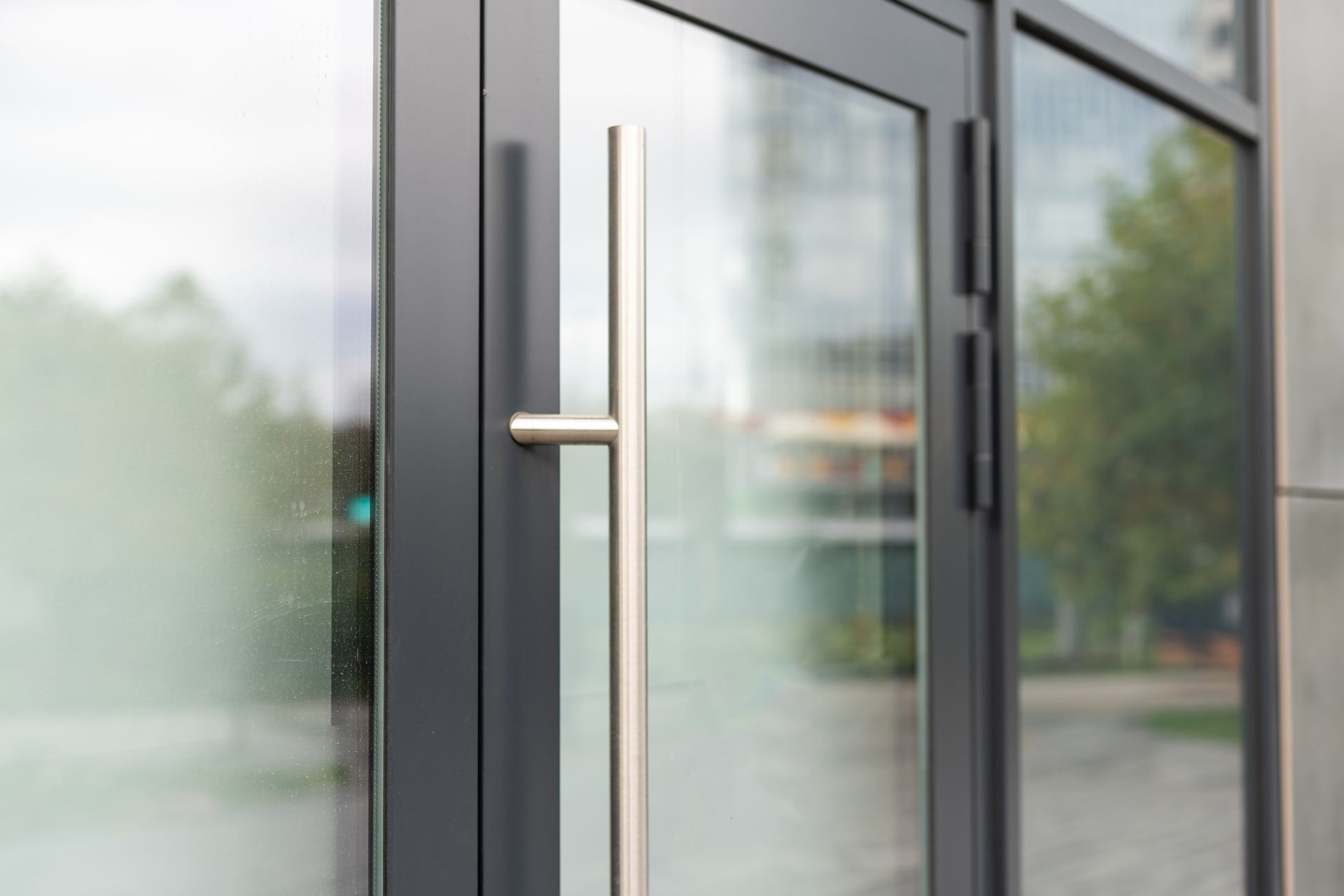 Glass Calimesa storefront door with a silver handle and blurred outdoor reflections