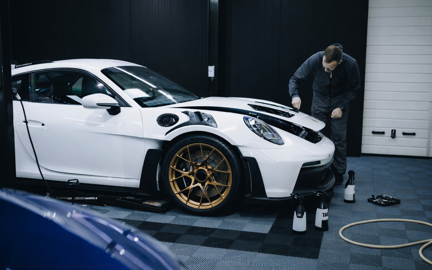 White sports car with gold rims getting windows tinted at $99 Tint Club in Yucaipa, CA near Calimesa, CA by a person in a garage