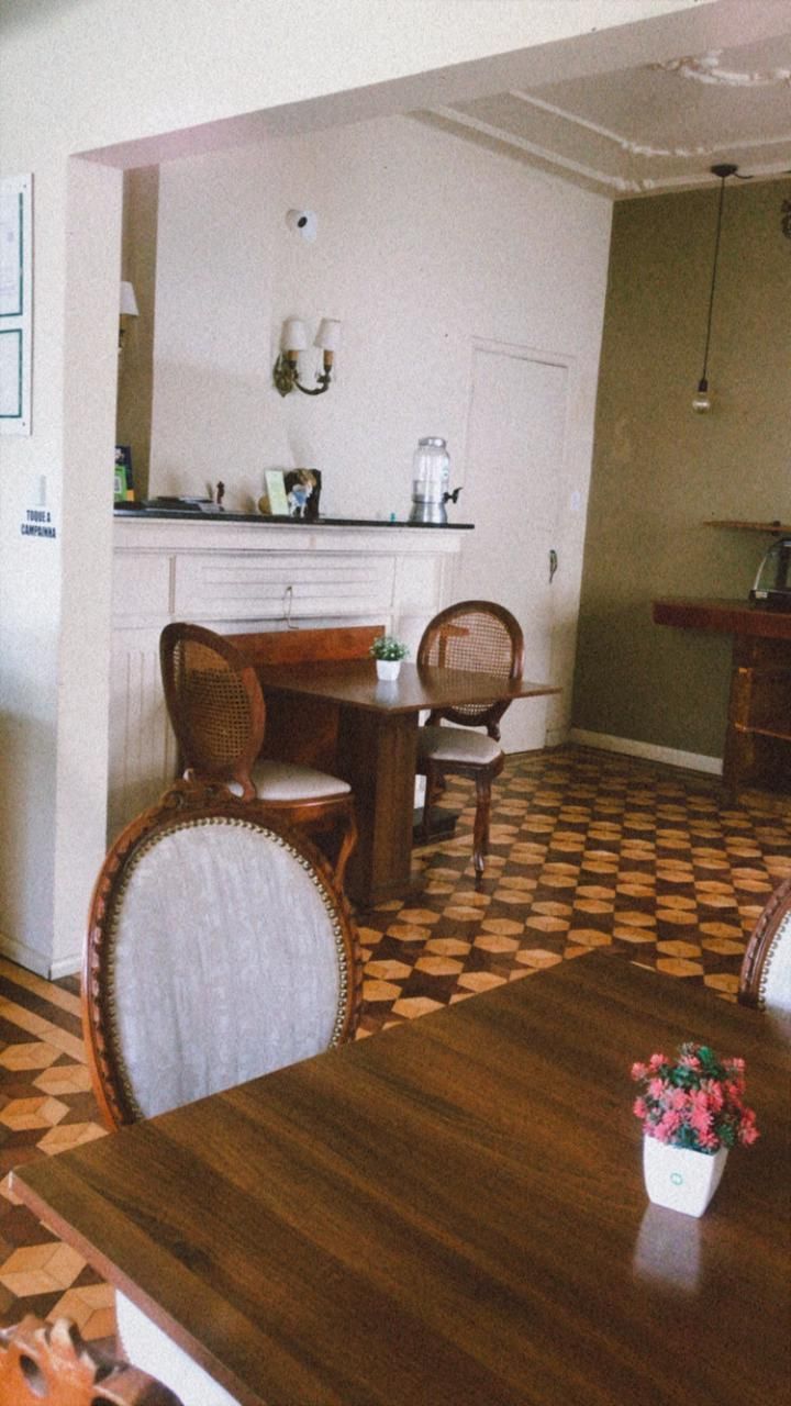 Interior de uma sala de jantar com mesa de madeira, piso de ladrilho estampado e cadeiras elegantes perto de uma lareira branca.
