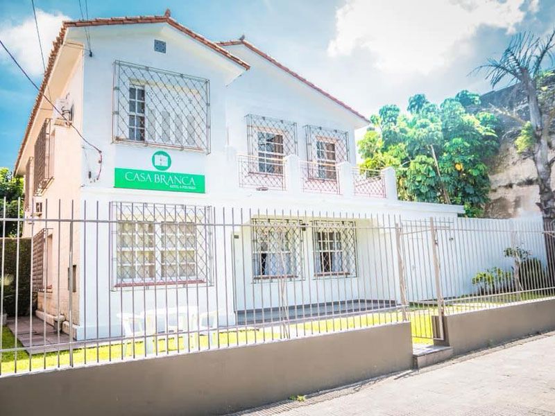 Um prédio branco de dois andares com uma placa verde 