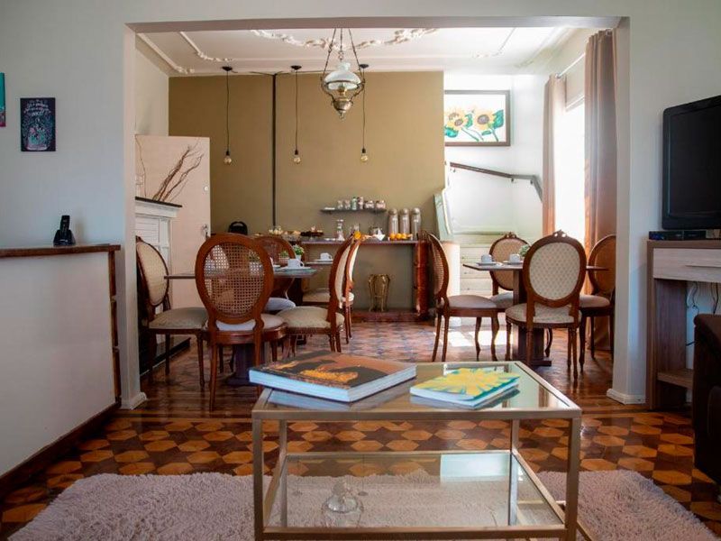 Uma sala de jantar com piso imitando madeira, uma mesa de centro em primeiro plano e cadeiras combinando ao redor das mesas de jantar.