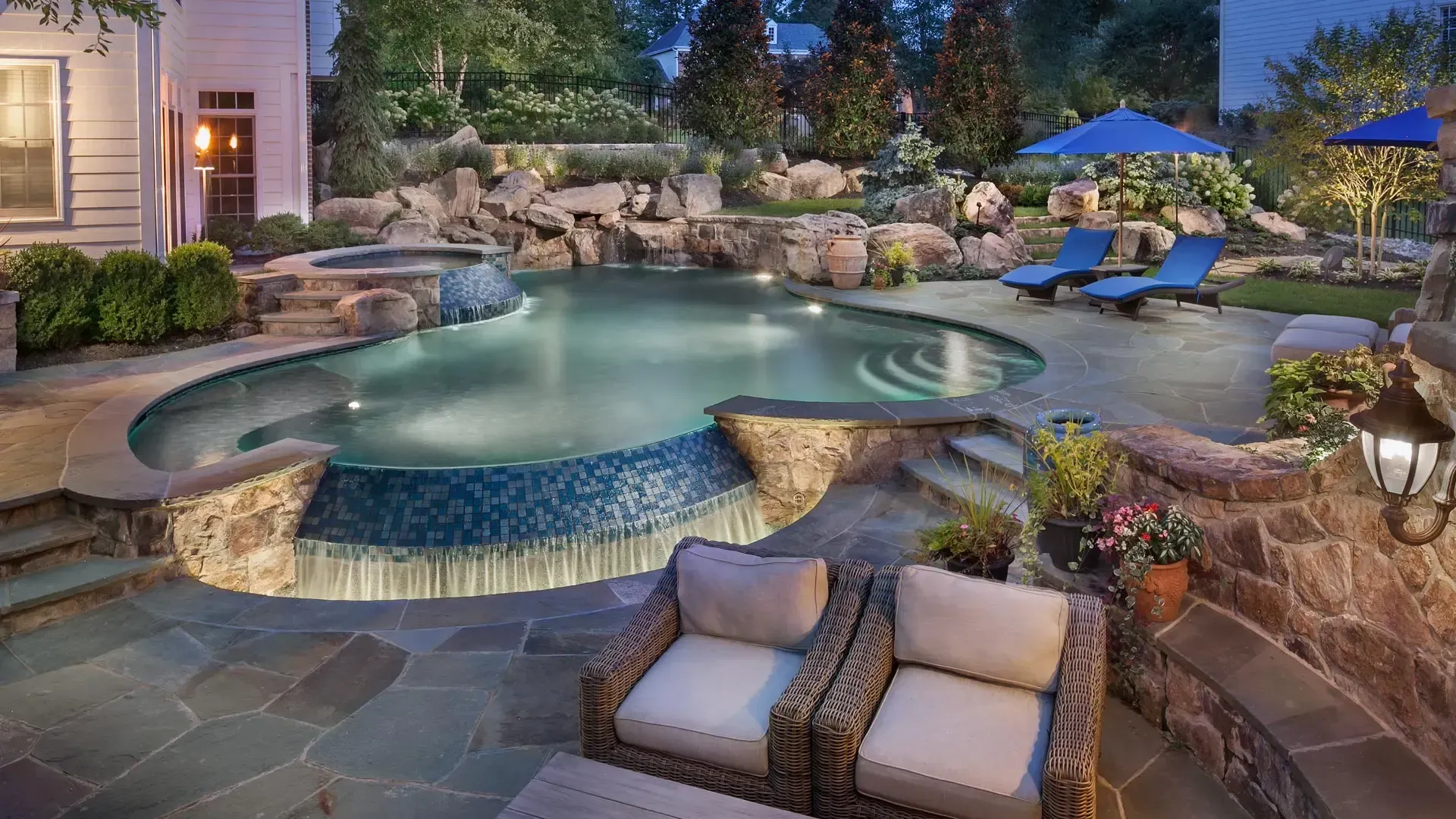 There is a large swimming pool in the backyard of a house.