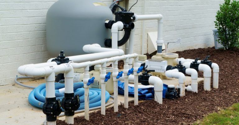 A swimming pool pump is sitting next to a bunch of pipes.