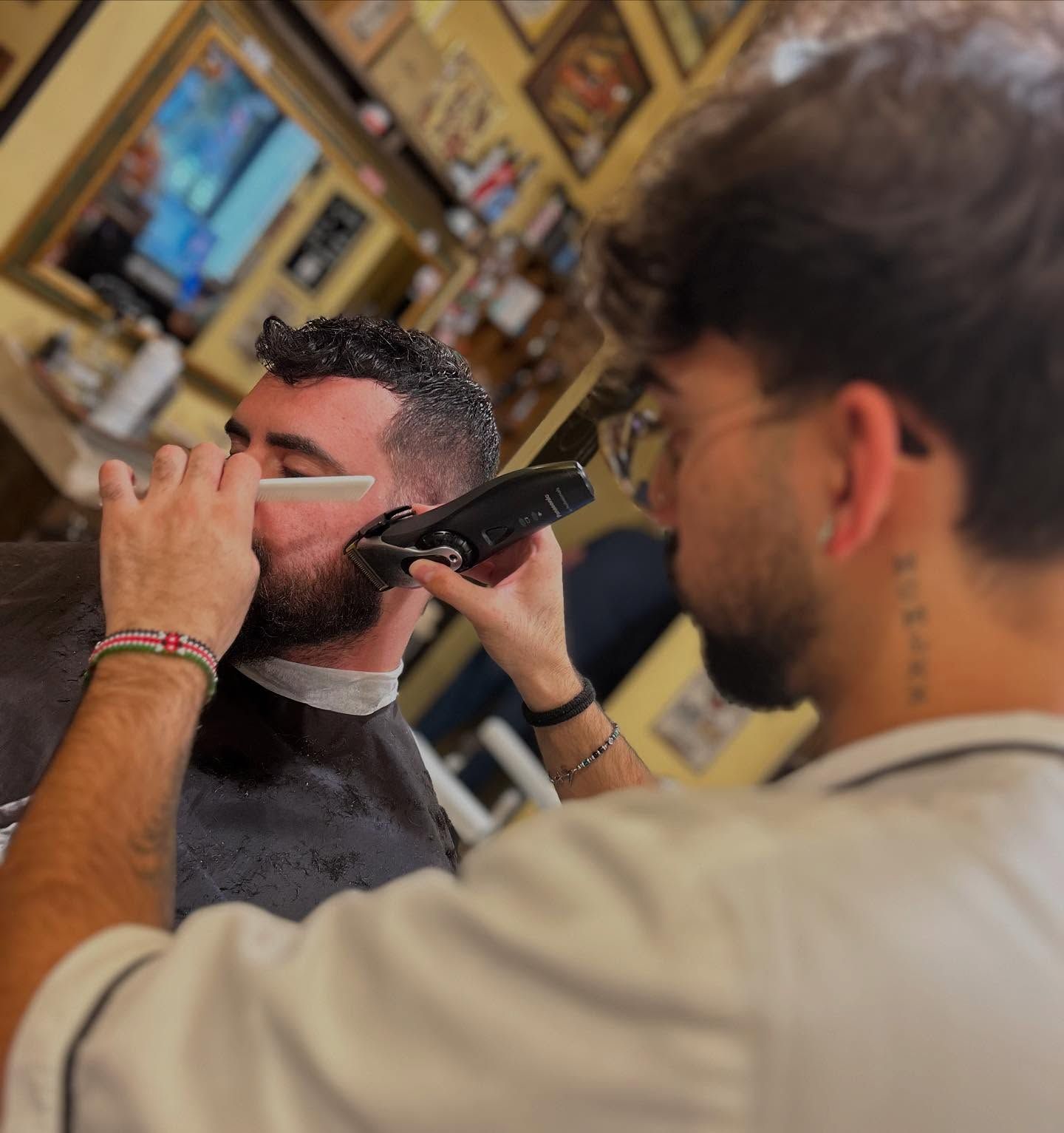Un uomo si sta facendo tagliare la barba da un barbiere