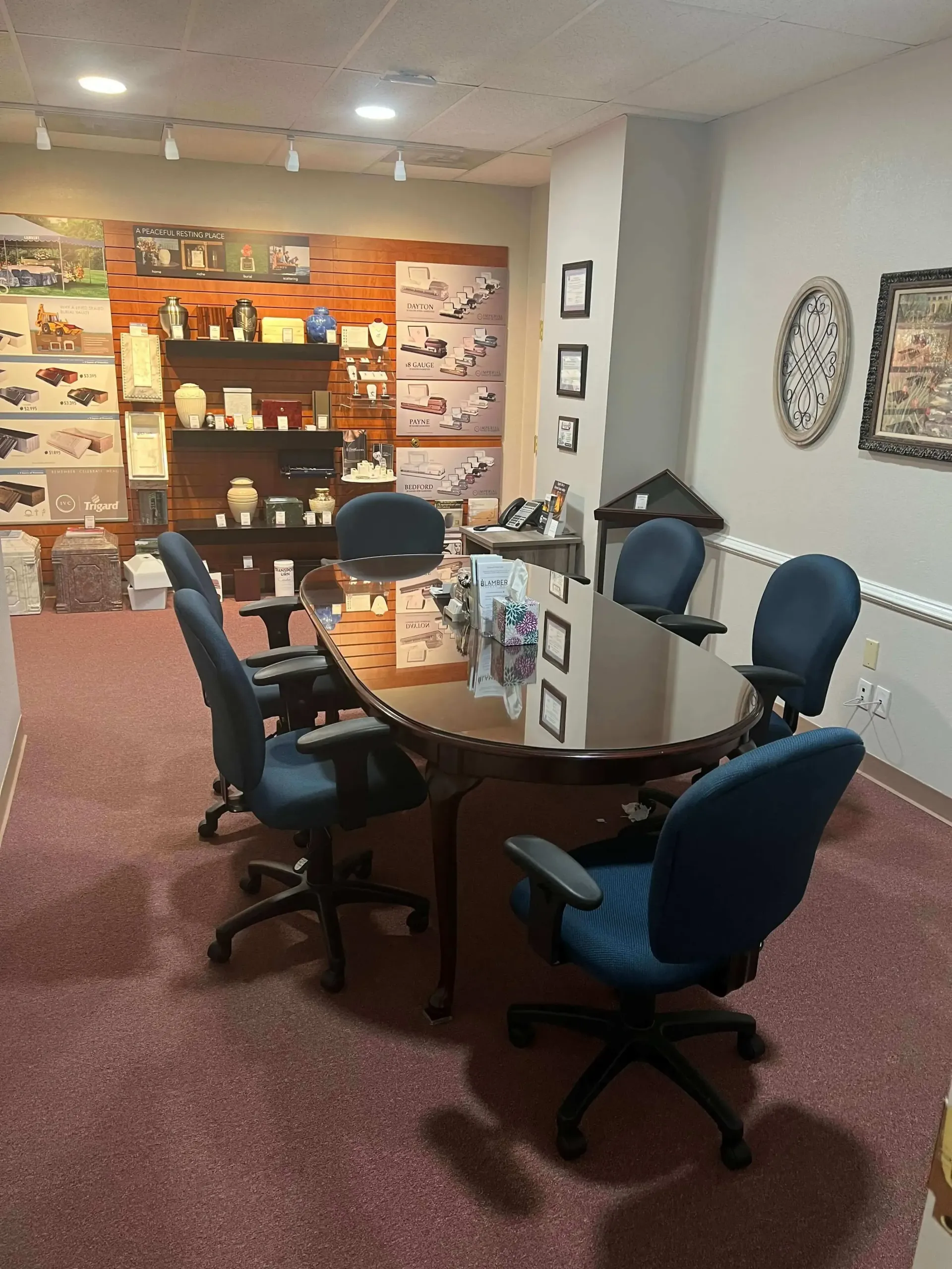 Office meeting area with round table, swivel chairs, and display shelves against the back wall.