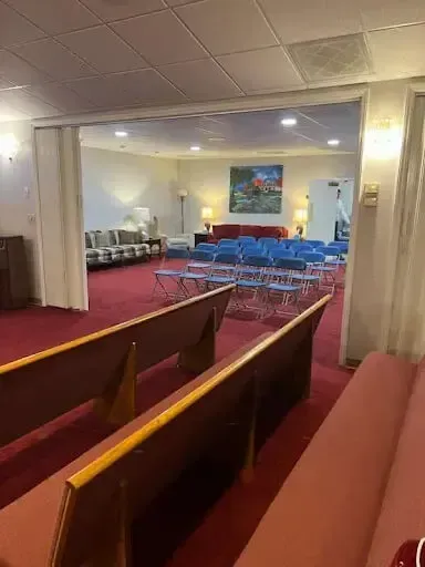 Church sanctuary with red carpet, wooden pews, and blue chairs facing the front stage