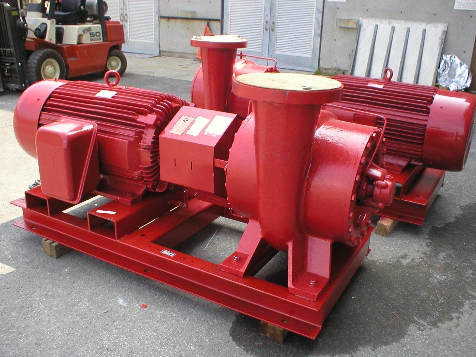 Deux pompes industrielles rouges montées sur un châssis métallique rouge, à l'extérieur.