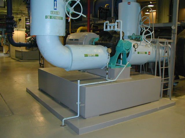 Grosse pompe à eau industrielle avec tuyaux blancs, moteur turquoise et socle gris dans une installation.