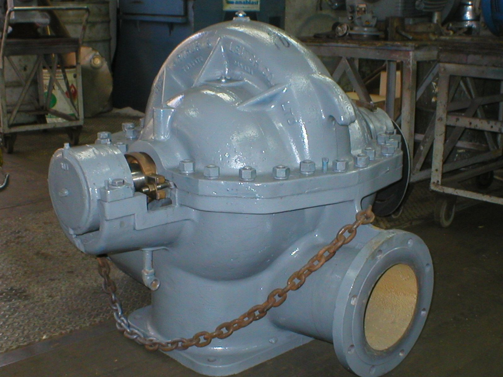 Grosse pompe industrielle grise à chaîne, dans un atelier.