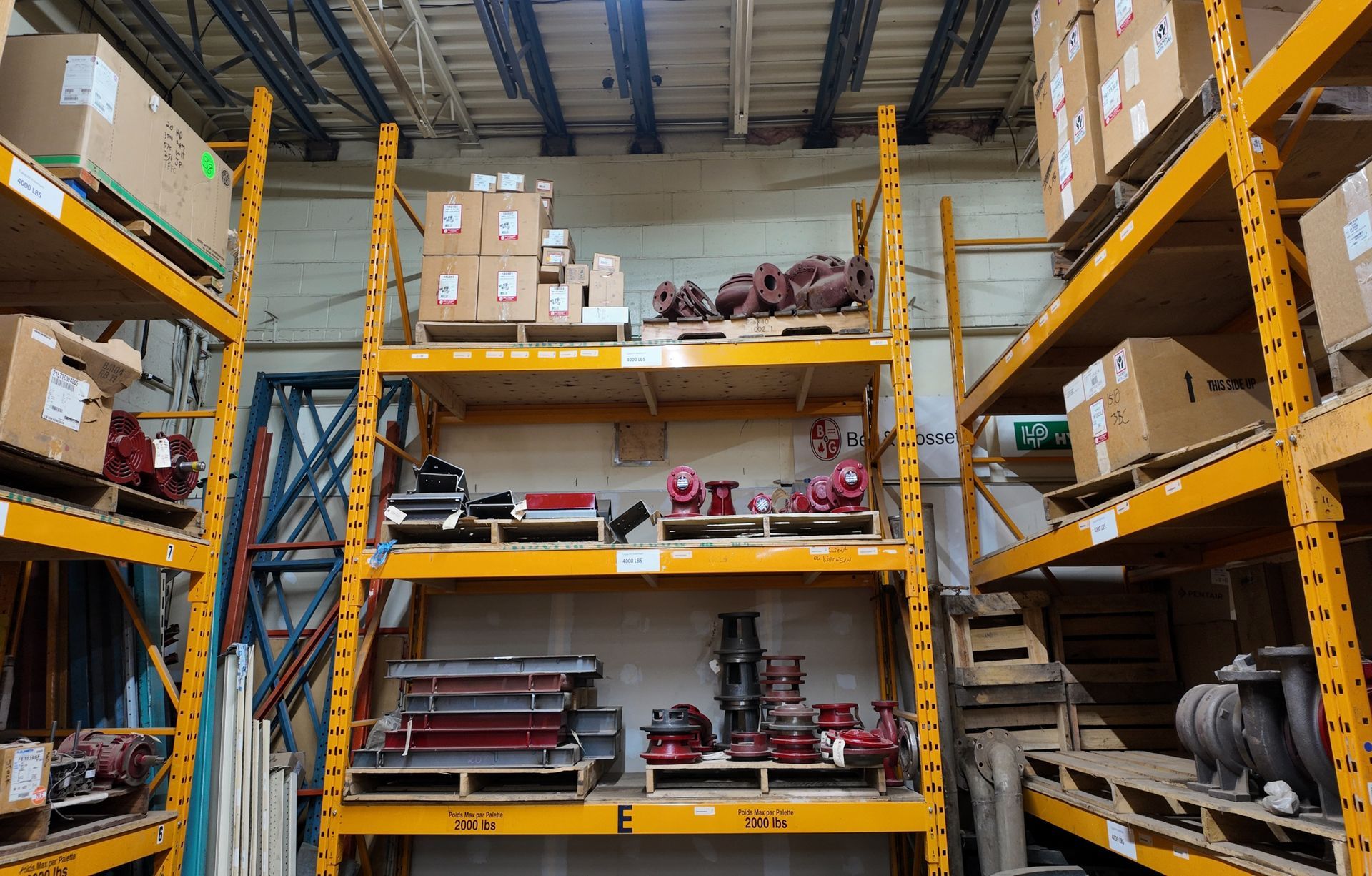 Des étagères jaunes d'entrepôt remplies de cartons et de matériel.