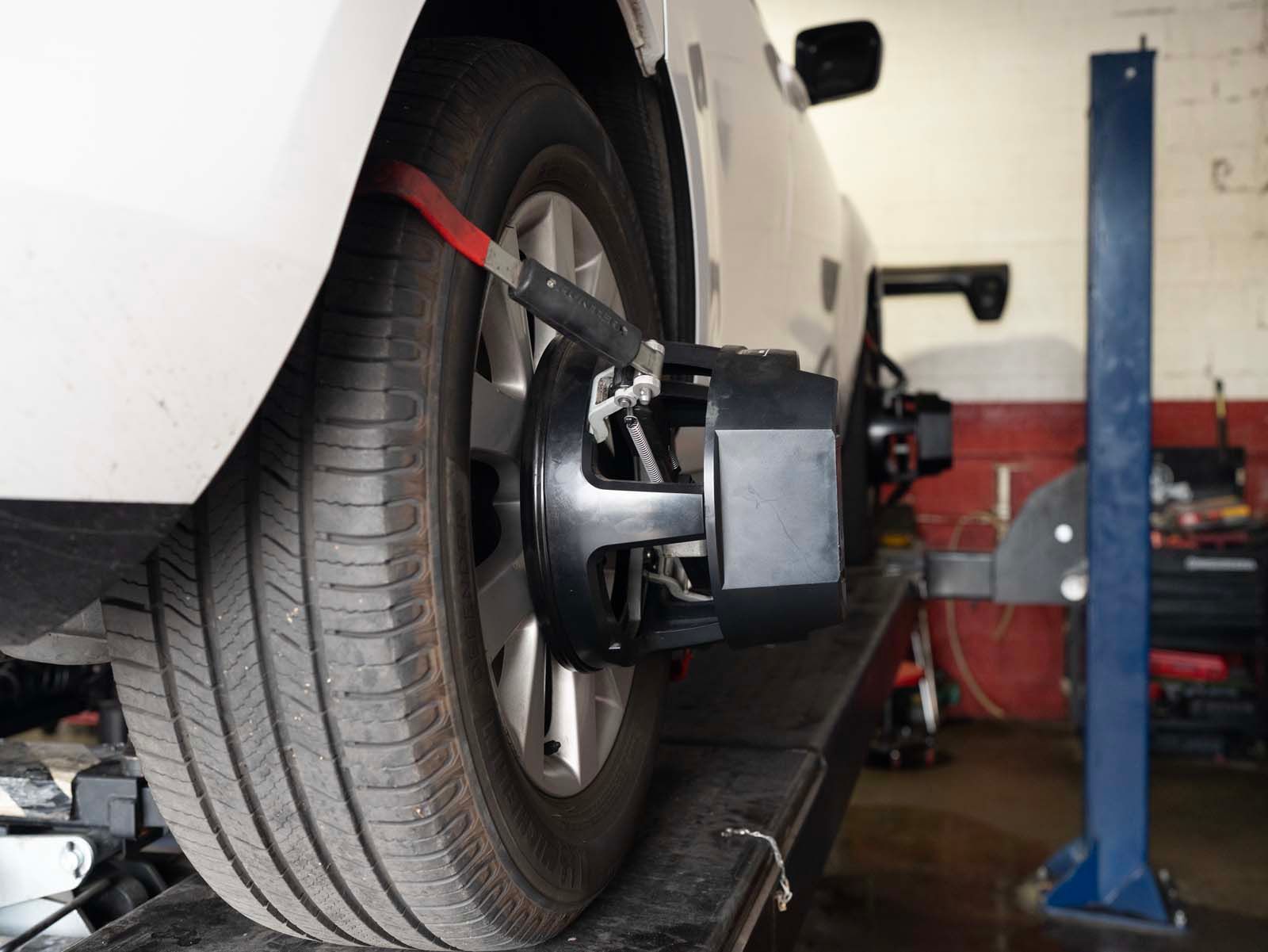 Car wheel on an alignment machine in an auto repair shop, with a blue lift in the background