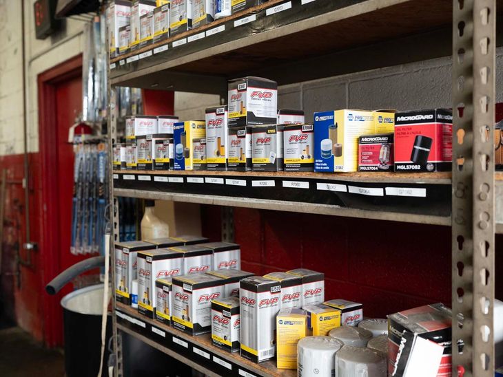Shelves of paint cans and supplies in a store aisle with red walls and metal shelving