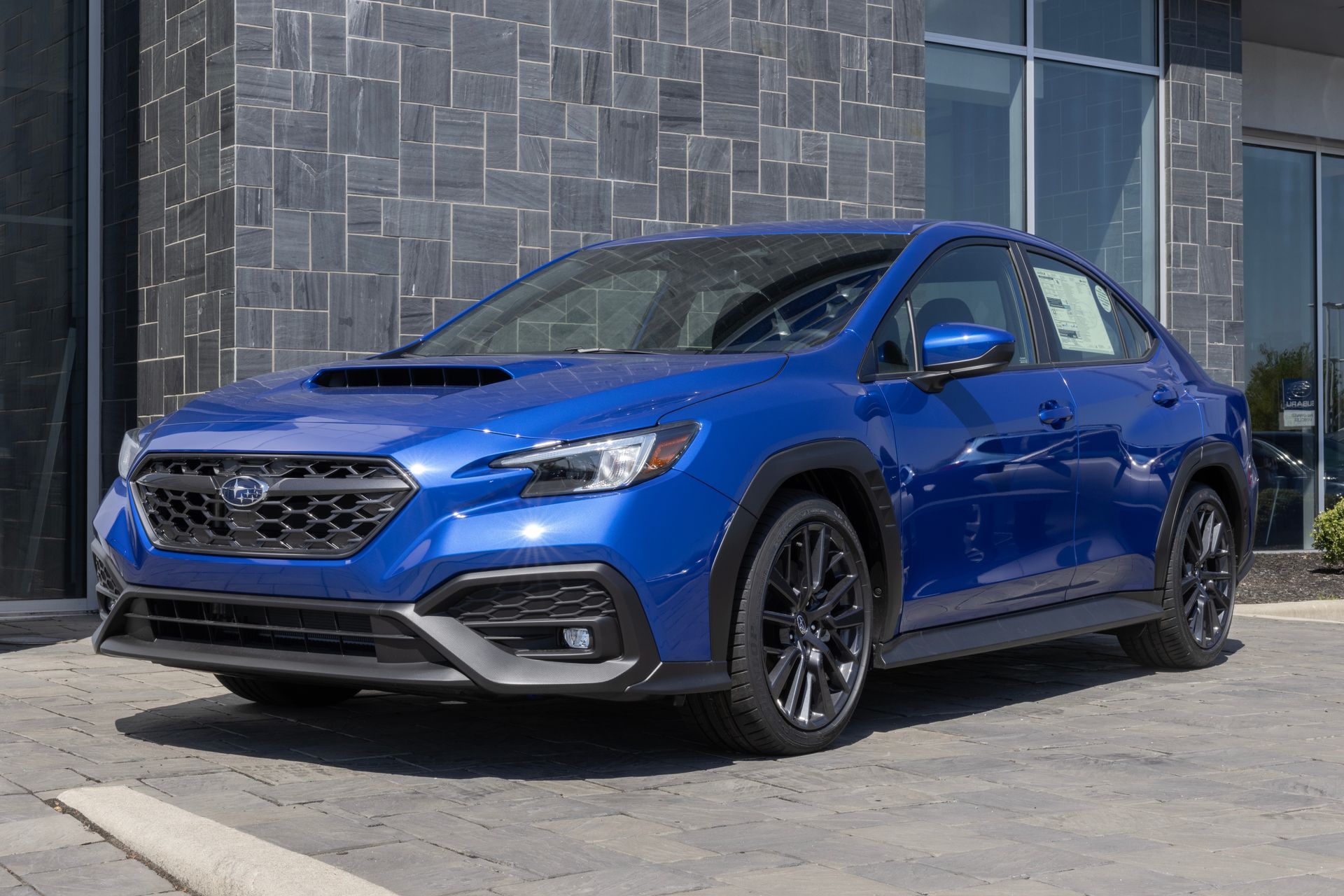 Blue Subaru sedan parked outside a building, front three-quarter view