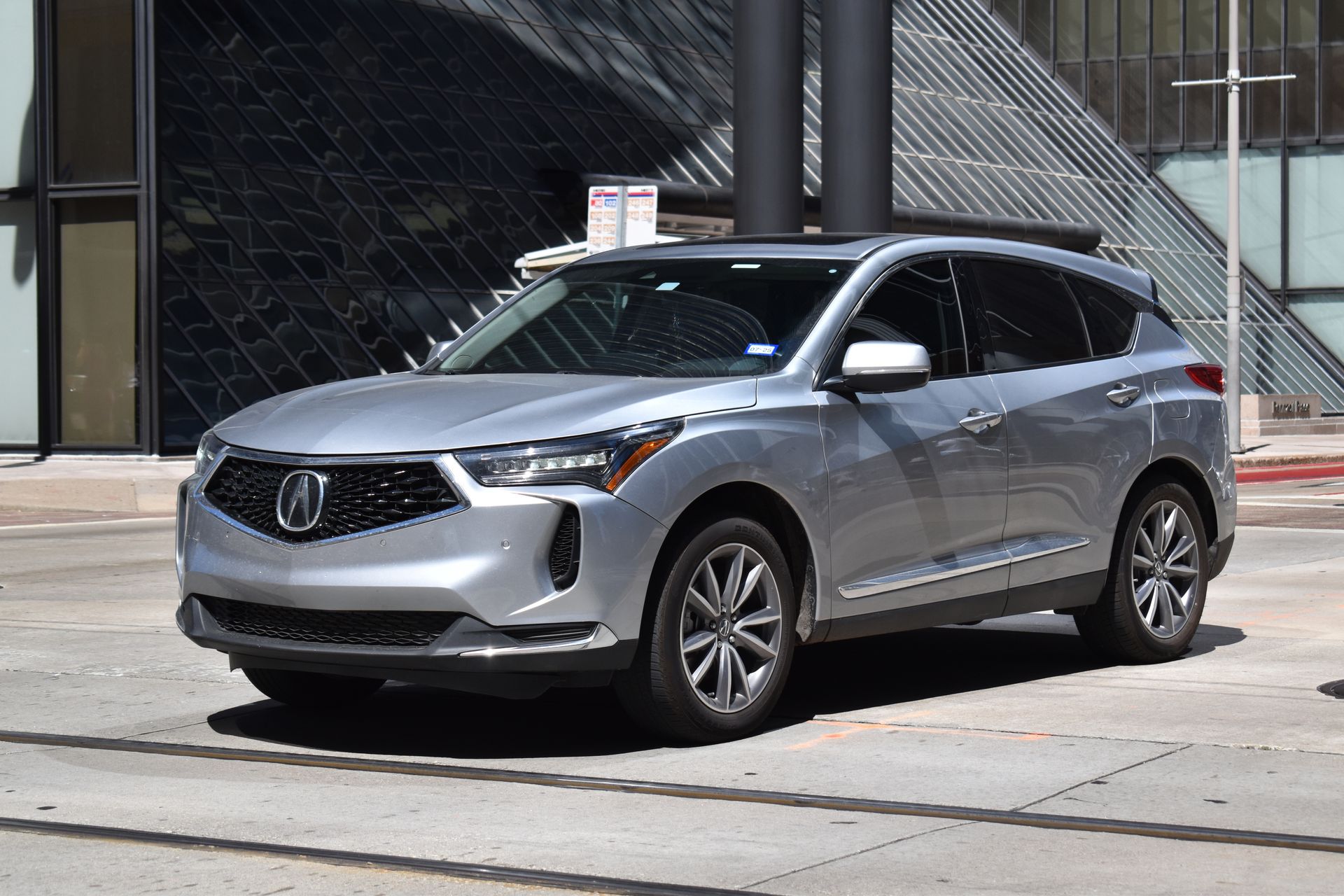 Silver SUV parked on a city street in front of modern buildings