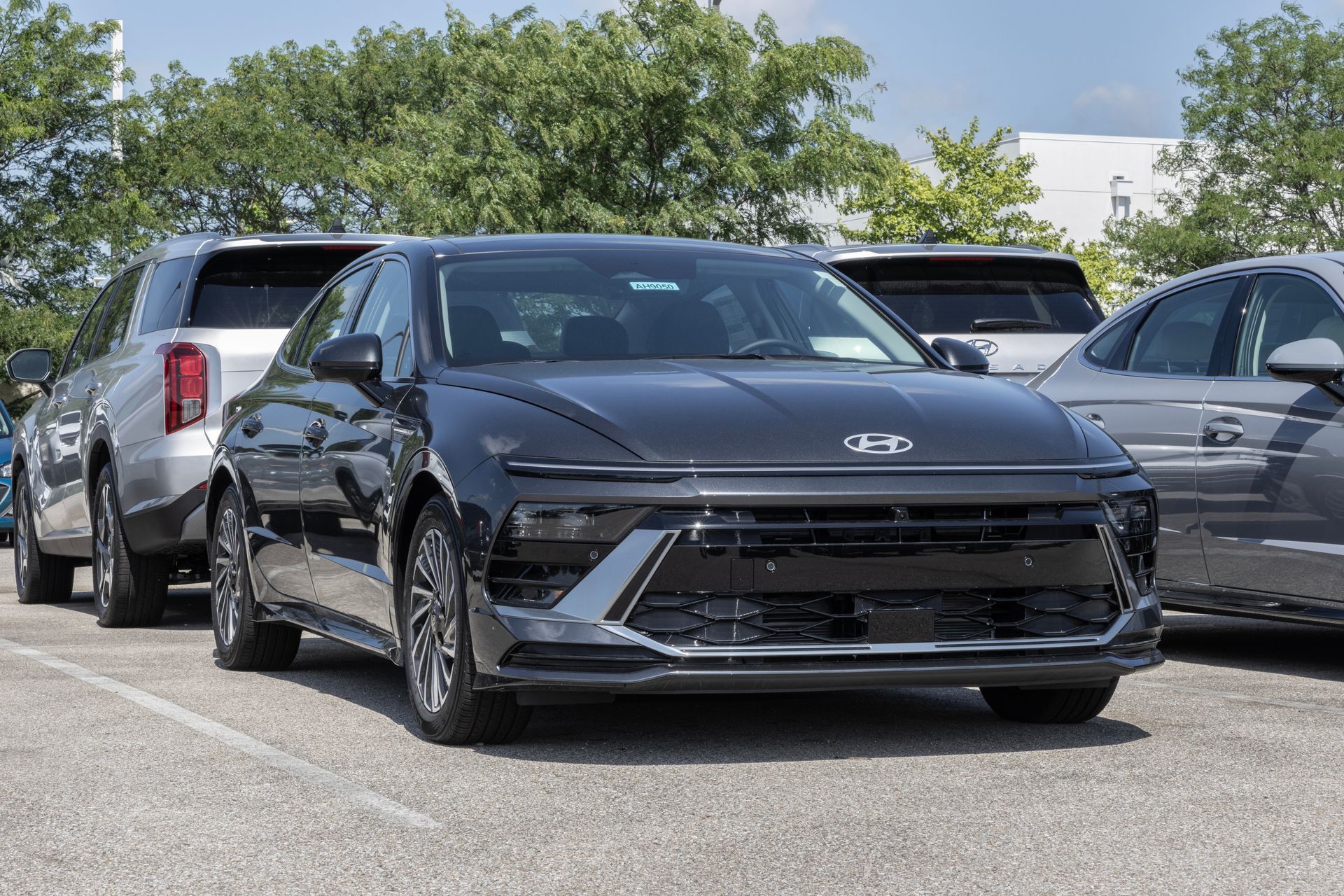 Black Hyundai sedan parked in a lot, viewed from the front, with other cars behind it