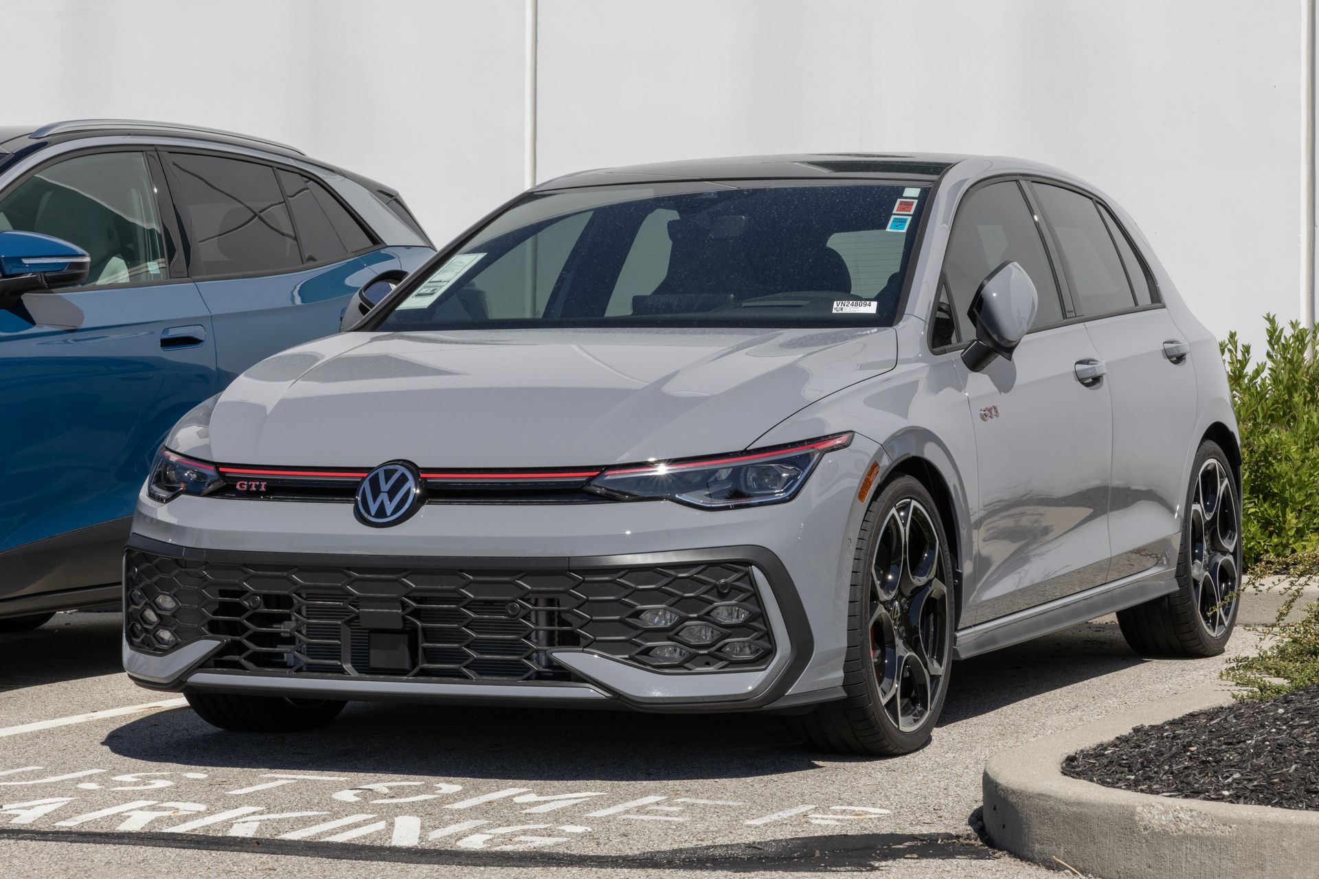 Gray Volkswagen hatchback parked outdoors beside a blue car