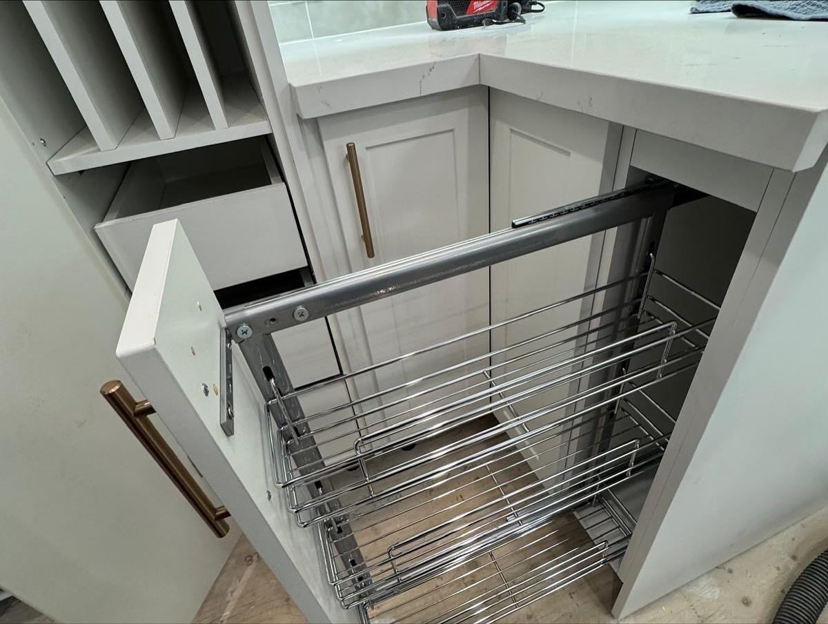Open pull-out wire pantry shelves in a white corner kitchen cabinet.