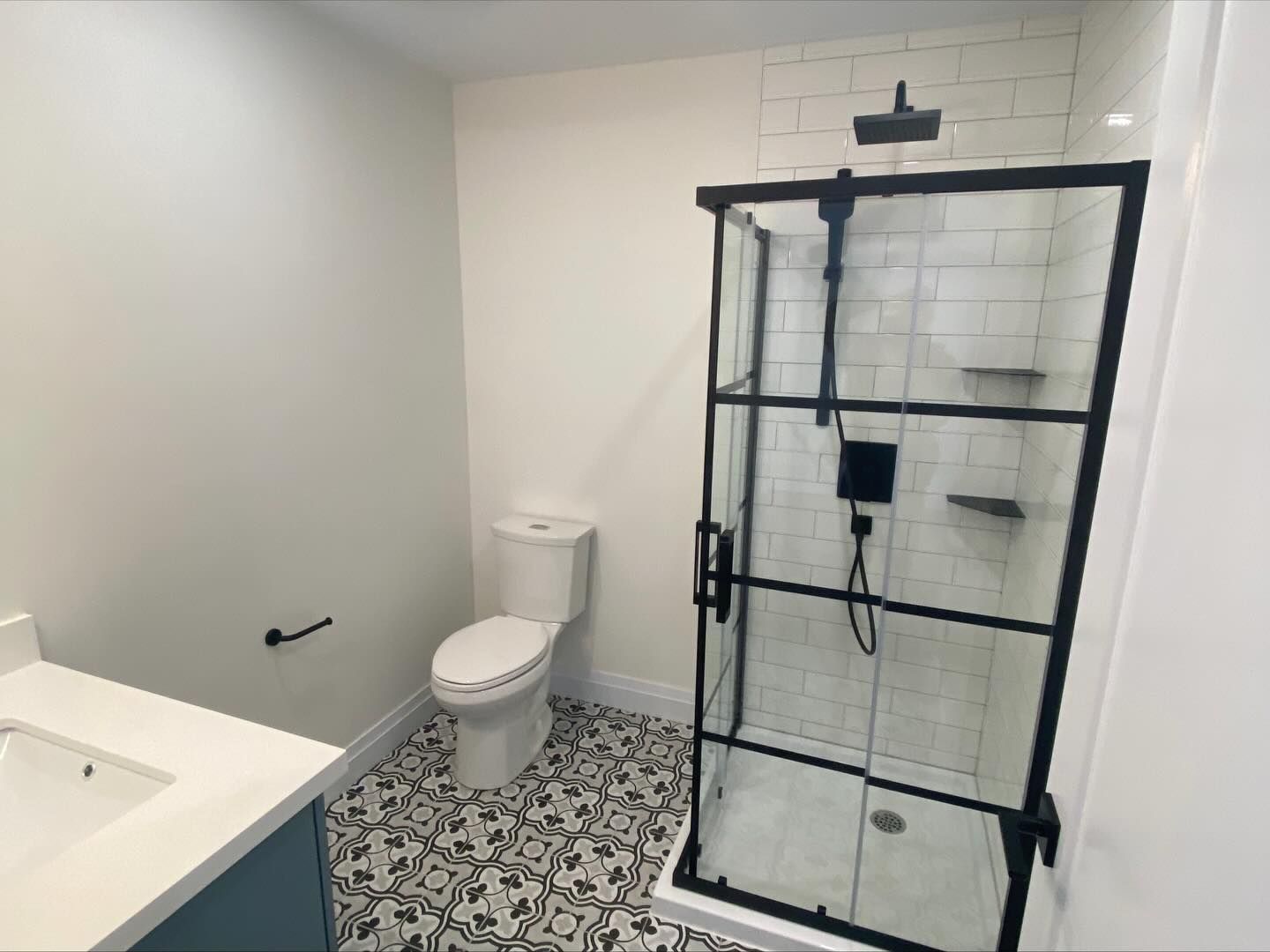 Bathroom with bathtub, toilet, and glass shower enclosure in white and black tile.