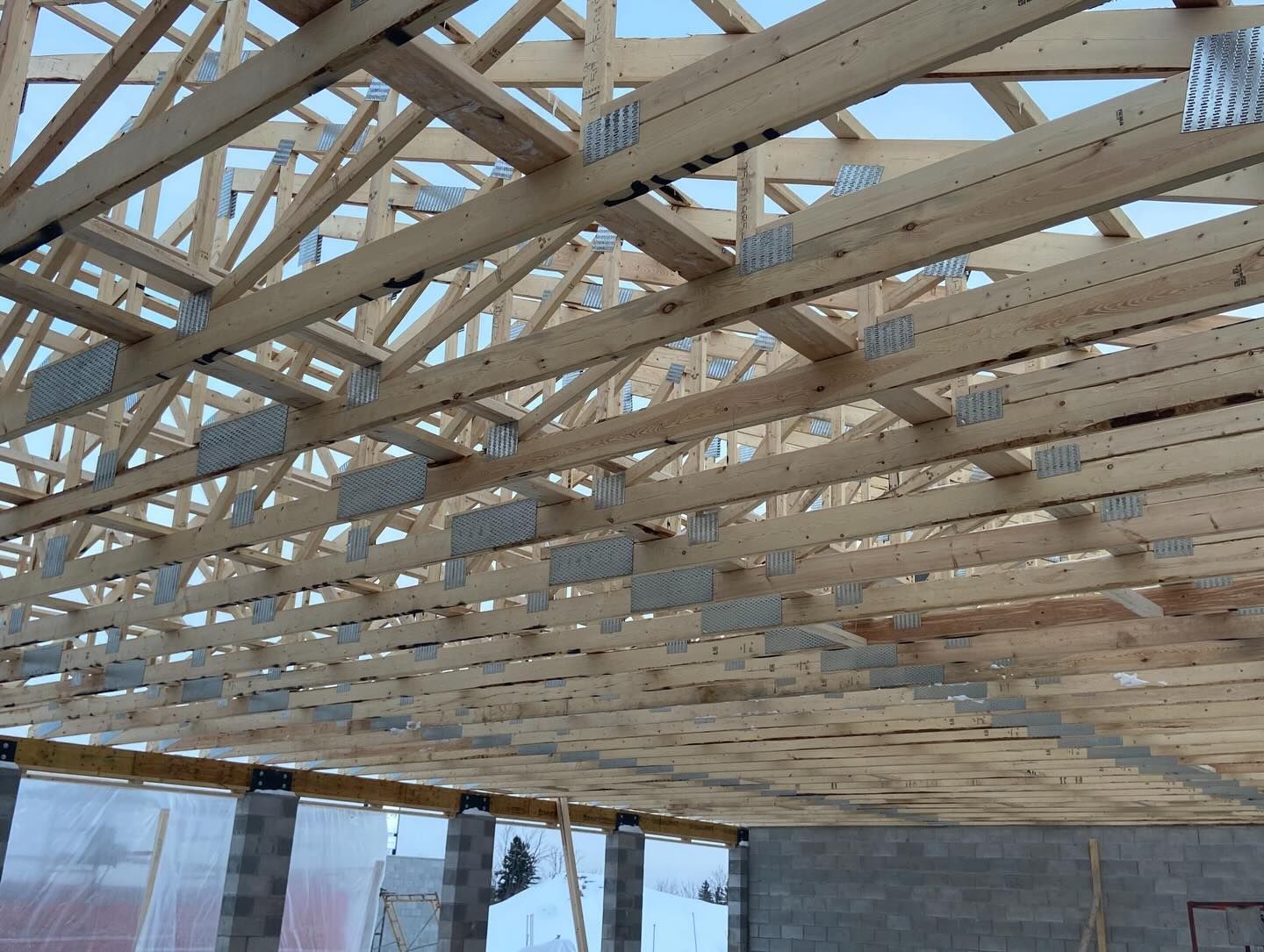 Wooden roof trusses under construction above a building frame, viewed from below