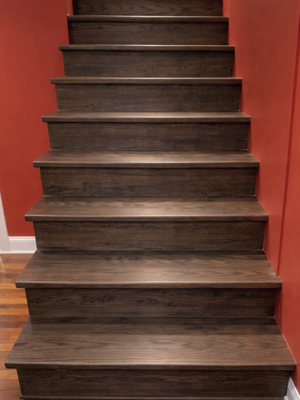 Dark wooden staircase with red walls on either side